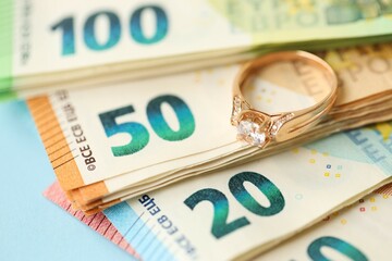 European union Euro money bills and coins with golden wedding ring on blue table