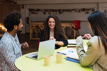 Colleagues with laptop having a meeting at table in office