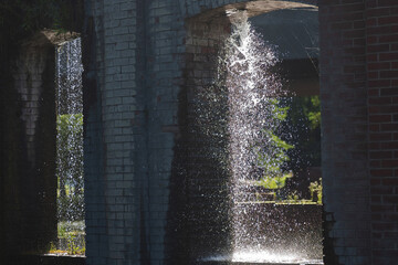 Fountain in the park. Water flows from the pipes of the bridge.