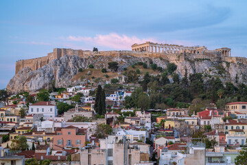 View of the Acropolis, in Athens, overlooking the old city, as the pink glow of early morning light illuminates the buildings and the Parthenon	