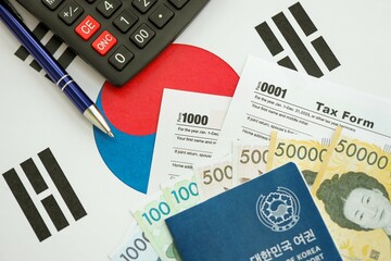 South Korean won money bills lies on table with pen, calculator, passport and tax forms