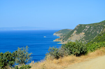 Obraz premium A beautiful blue ocean with a mountain in the background. The sky is clear and the sun is shining
