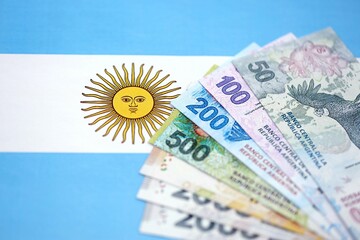 Argentine pesos money bills in big amount lies on Argentina flag close up