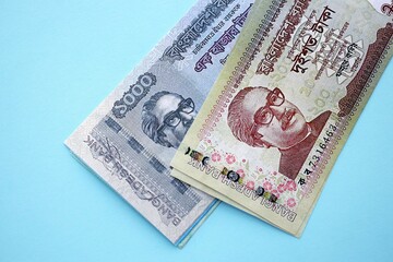 Bangladeshi taka money bills in big amount lies on teal color table close up