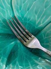 A high-angle, close-up shot focuses on a well-used silver dining fork, positioned diagonally on a...