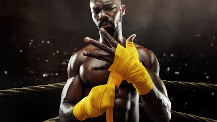 Close-up of a boxer preparing for a fight by wrapping yellow bandages, shot on a 3D boxing ring....