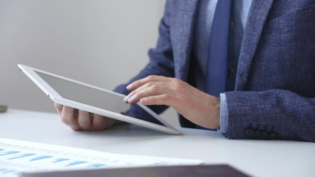 Businessman is using a digital tablet to analyze financial data, working with modern technology in the office to improve productivity and decision making. Business people concept - Powered by Adobe