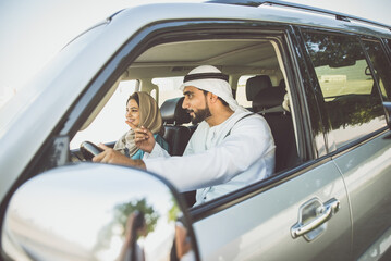 Happy couple driving the car in Dubai. Man and woman going out for shopping. Concept about...