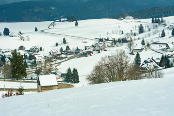 Snow blanketed village nestled in tranquil mountains creates a picturesque winter landscape,...