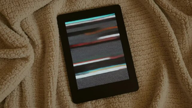E-reader displaying flickering screen placed on a cozy blanket  