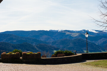 Breathtaking view of rolling hills and snow-capped mountains under a clear blue sky from a scenic...
