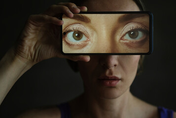 Person holding smartphone with eye display representing digital identity