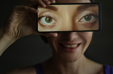 Person holding smartphone with eyes on screen depicting virtual identity