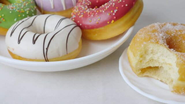 Donuts with sugar sprinkles with bite mark on a white background.