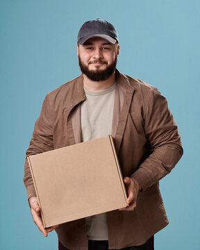 Man in casual clothing holding a cardboard box in a studio portrait