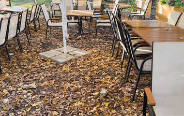 table and chairs of a street cafe in autumn leaves.
