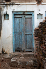 A blue door in a wall in the village of Alīpura, Uttar Pradesh
