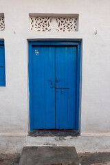 A blue door in a wall in the village of Alīpura, Uttar Pradesh