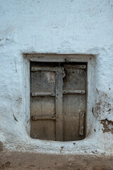 A brown door in a wall in the village of Alīpura, Uttar Pradesh
