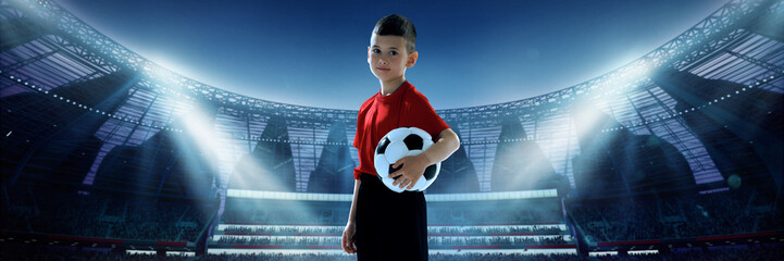 A young soccer player in a red jersey holds a ball on an illuminated 3D stadium field under bright spotlights. Concept of children's dreams in professional sports
