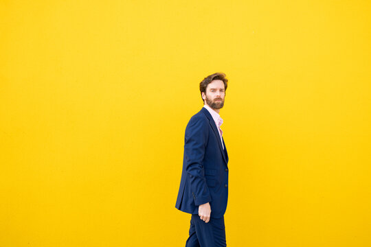 Confident businessman in suit against yellow background