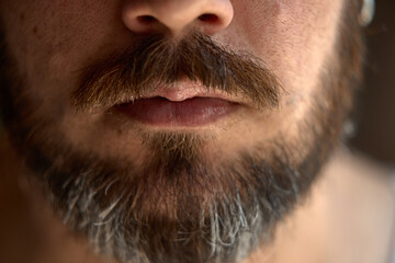 Obraz premium A close-up view shows a man's lips adorned by a thick beard and mustache. Concept of masculinity and grooming trends.
