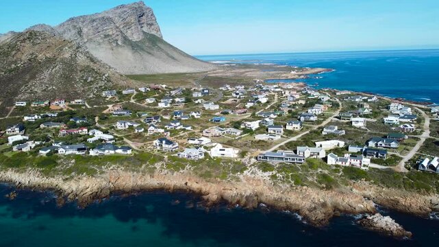 Camera moving sideways along the coast and looking to the small town of Pringle Bay, 4K aerial video.