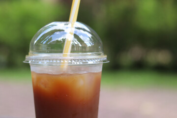 Bumble coffee. Coffee with juice in a disposable plastic cup with a straw. Coffee with orange juice, syrup and ice. Refreshing drink, rest for pedestrians in hot weather. Takeaway drink, close-up