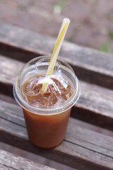 Bumble coffee. Coffee with juice in a disposable plastic cup with a straw. Coffee with orange juice, syrup and ice. Refreshing drink, rest for pedestrians in hot weather. Takeaway drink, close-up