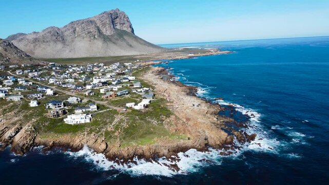 Camera panning up along the coast of the small town of Pringle Bay, 4K aerial video