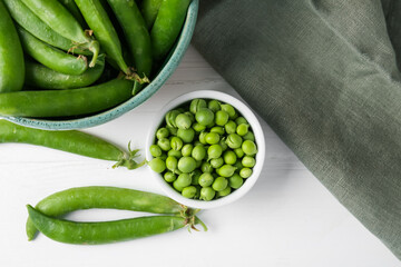 Fresh ripe green peas on white wooden table, flat lay