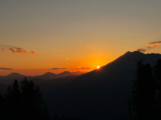 Majestic sunset over mountain range, with vibrant orange and yellow hues illuminating the sky,...