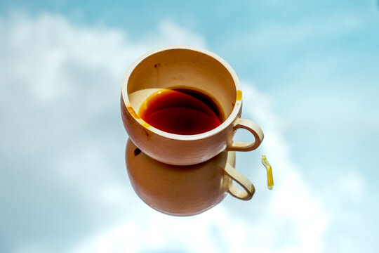 Creative image of a coffee cup reflecting in the sky with clouds
