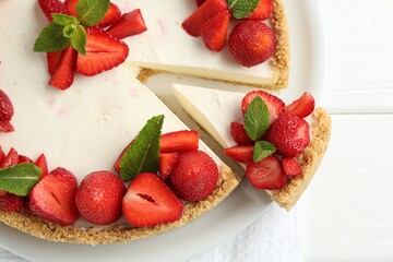 Delicious cheesecake with strawberries and mint on white wooden table, top view