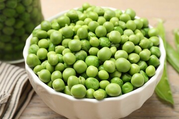 Fresh green peas in bowl and pods on table, closeup. Pickling vegetables