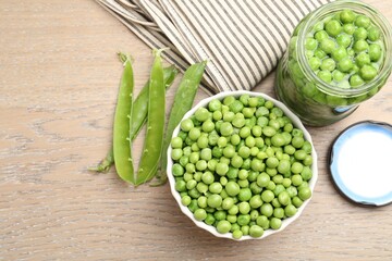 Fresh green peas in bowl, jar and pods on wooden table, flat lay. Pickling vegetables