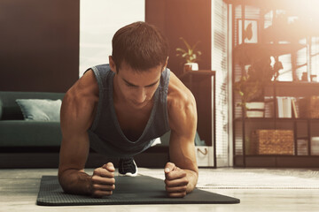 Sporty man doing plank exercise on fitness mat at home