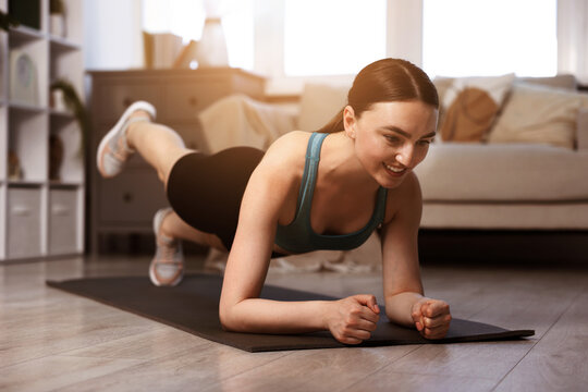 Young woman doing plank exercise on fitness mat at home. Sport and healthy lifestyle