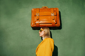 Stylish woman in yellow with vintage suitcase on head