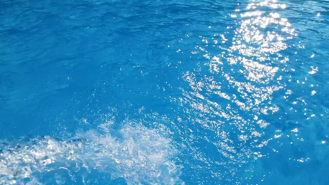 Video footage of blue clear water falling into a blue pool.
