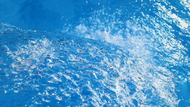 Video footage of blue clear water falling into a blue pool.