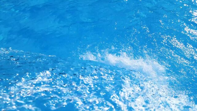Video footage of blue clear water falling into a blue pool.