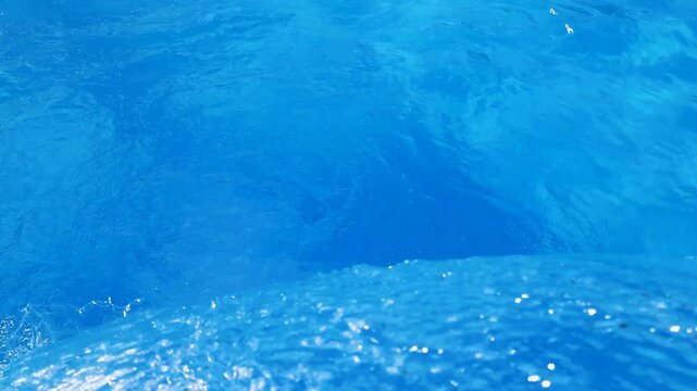 Video footage of blue clear water falling into a blue pool.