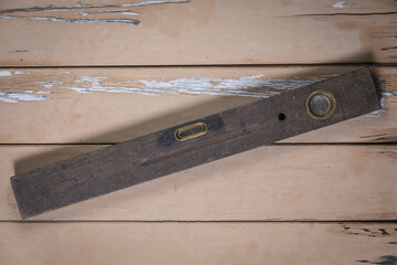 Ancient wooden spirit level placed slightly diagonally in the center on a rustic beige wooden...