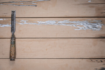 Old chisel placed on the left edge of a rustic beige wooden table. Space is left free for text or...