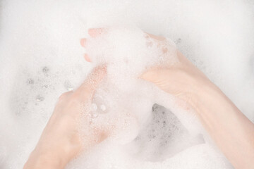 Fototapeta premium Female hands in foam close-up. girl's hands in soap foam. washing, cleaning, washing dishes