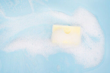 White pure foam with sponge for washing dishes on blue background. dishwashing foam close up