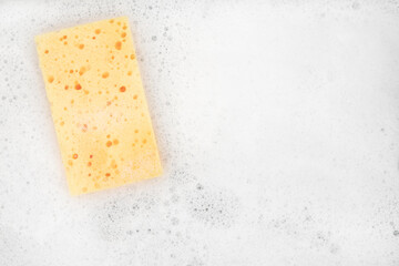 White pure foam with sponge for washing dishes. dishwashing foam and yellow sponge close up