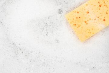 White pure foam with sponge for washing dishes. dishwashing foam and yellow sponge close up