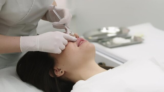 A beautician performing beauty injections on a young woman in a modern cosmetic clinic. Concept of skin rejuvenation, cosmetic procedures, and non-surgical facial enhancements for a youthful look.